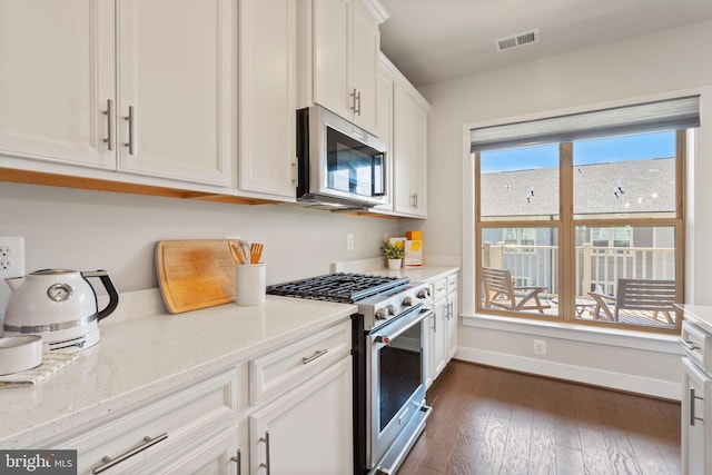 kitchen featuring visible vents, baseboards, dark wood finished floors, appliances with stainless steel finishes, and white cabinetry