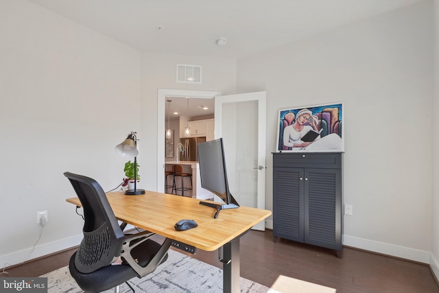 home office with wood finished floors, visible vents, and baseboards