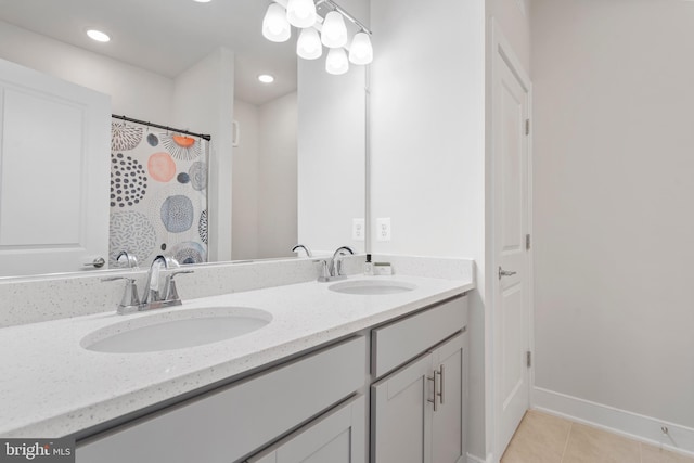 full bathroom featuring tile patterned flooring, double vanity, baseboards, and a sink