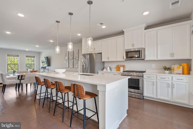 kitchen featuring a center island with sink, visible vents, appliances with stainless steel finishes, and dark wood-type flooring