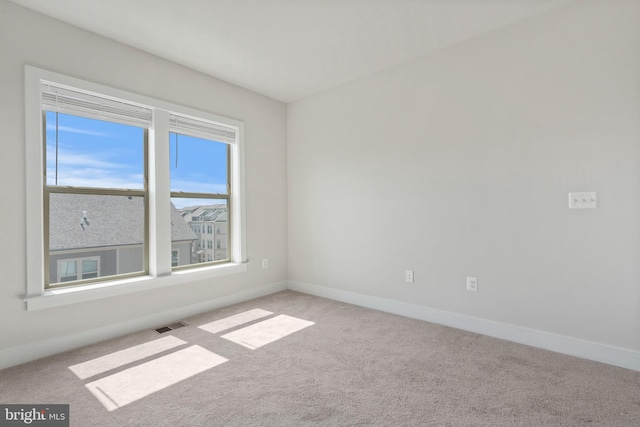 spare room featuring visible vents, light carpet, and baseboards