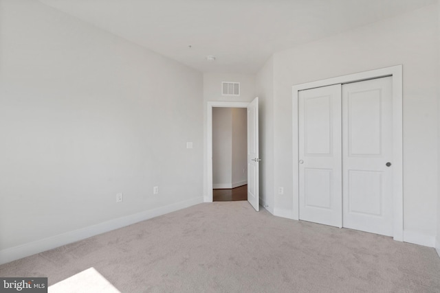 unfurnished bedroom with visible vents, baseboards, a closet, and carpet flooring