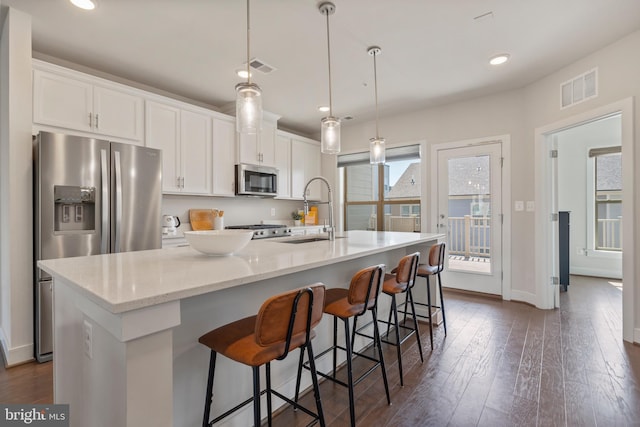 kitchen featuring dark wood-type flooring, visible vents, stainless steel appliances, and a sink