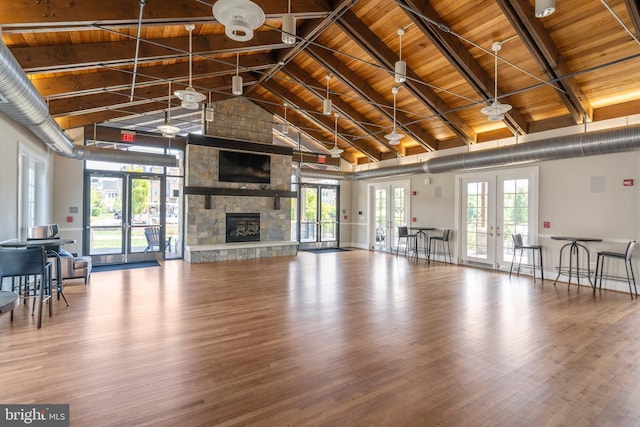 unfurnished living room with a stone fireplace, french doors, wood ceiling, and wood finished floors