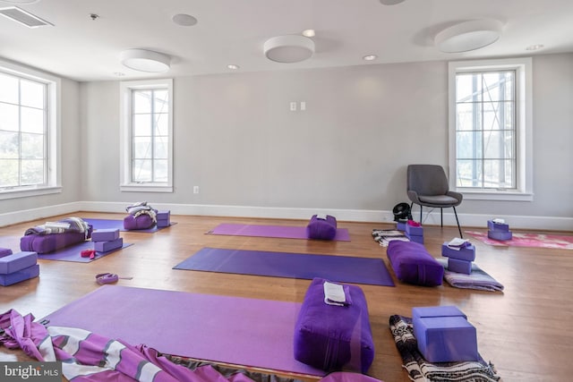 exercise room with baseboards, plenty of natural light, visible vents, and wood finished floors