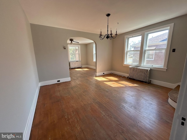 interior space featuring baseboards, arched walkways, wood-type flooring, and radiator heating unit