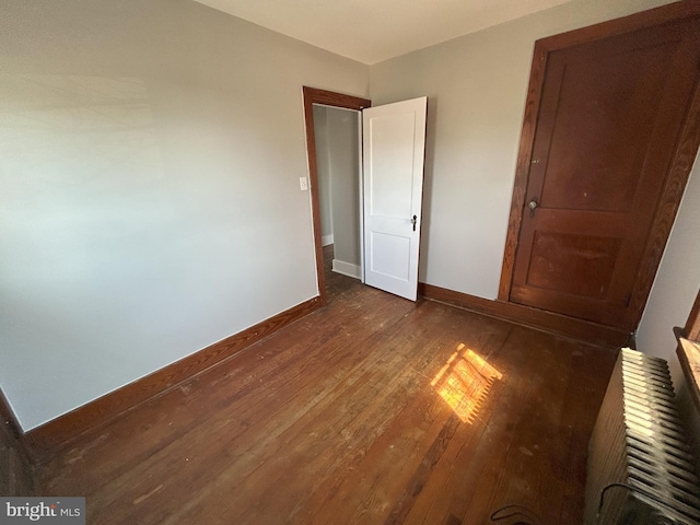 unfurnished bedroom with baseboards and dark wood-style flooring