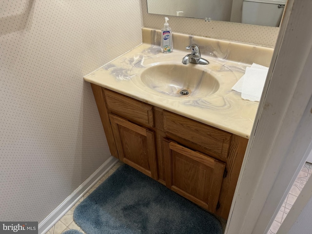 bathroom featuring tile patterned floors, wallpapered walls, vanity, and baseboards