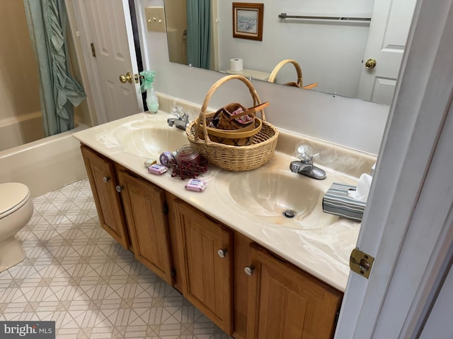 full bathroom featuring a sink, toilet, double vanity, and tile patterned floors