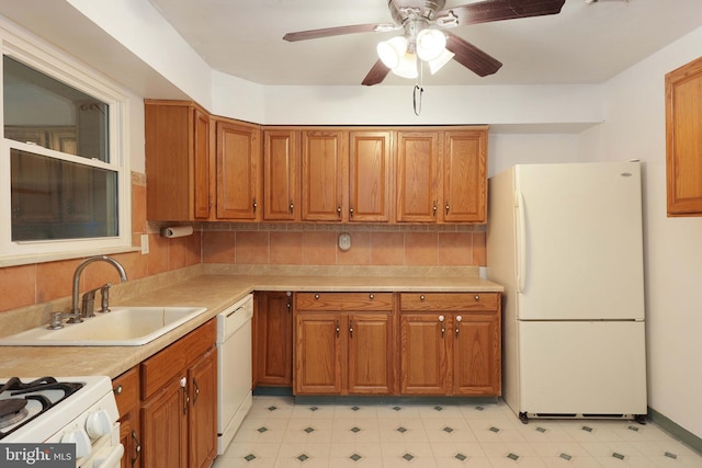 kitchen with brown cabinetry, white appliances, light countertops, and a sink