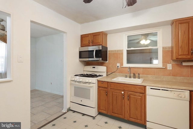 kitchen with white appliances, light countertops, a ceiling fan, and a sink