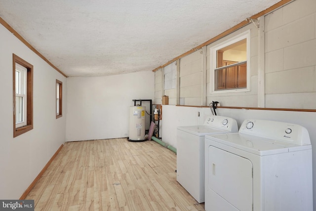 clothes washing area with light wood-type flooring, electric water heater, a textured ceiling, separate washer and dryer, and laundry area