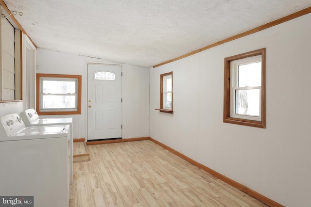 clothes washing area with washer and dryer, a textured ceiling, a wealth of natural light, and laundry area