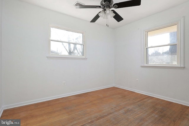 spare room with visible vents, a ceiling fan, baseboards, and wood-type flooring