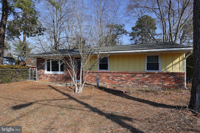 view of front facade with board and batten siding, fence, and brick siding