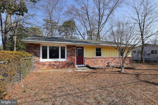 ranch-style home with brick siding, board and batten siding, and fence