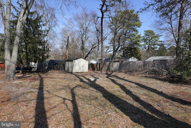 view of yard featuring an outbuilding, fence, and a shed