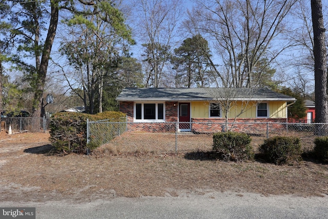 view of front facade with board and batten siding, brick siding, and a fenced front yard