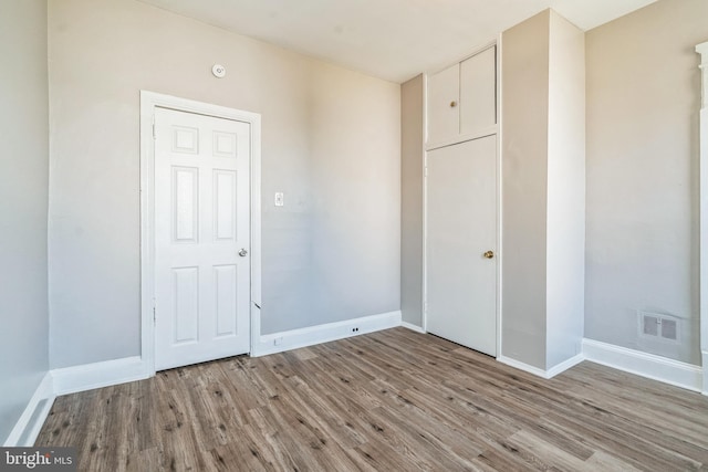 unfurnished bedroom featuring wood finished floors, visible vents, and baseboards