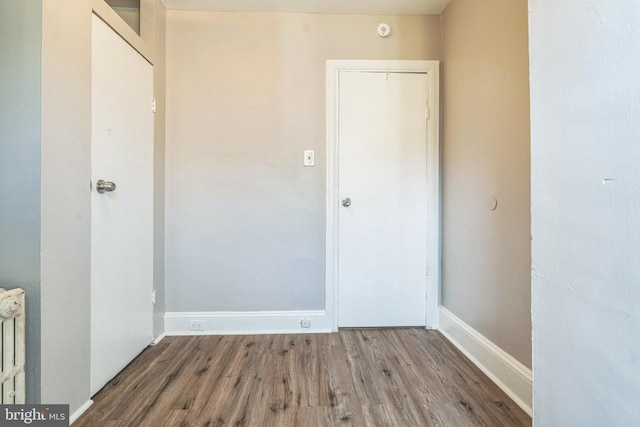 spare room with baseboards and wood finished floors