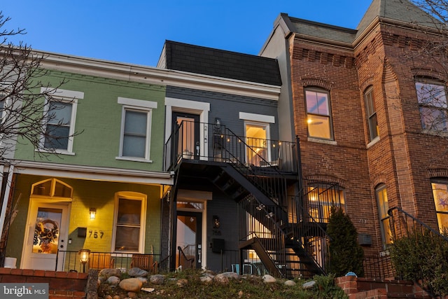 view of property featuring stairs, a porch, and brick siding