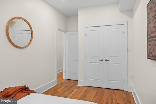 bedroom with a closet, baseboards, and light wood-style floors