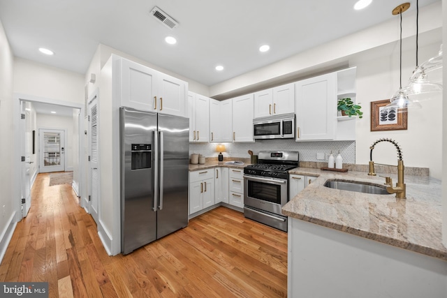 kitchen featuring light stone counters, open shelves, a sink, white cabinets, and appliances with stainless steel finishes