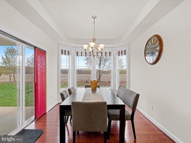 23811 Pembroke Ln, Millville, DE 19967 - dining area featuring dark wood-style flooring, a tray ceiling, baseboards, and an inviting chandelier