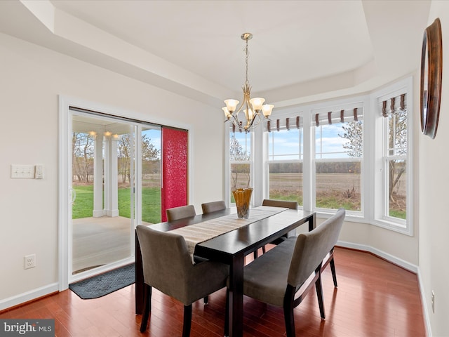 23811 Pembroke Ln, Millville, DE 19967 - dining area featuring a tray ceiling, wood finished floors, an inviting chandelier, and baseboards