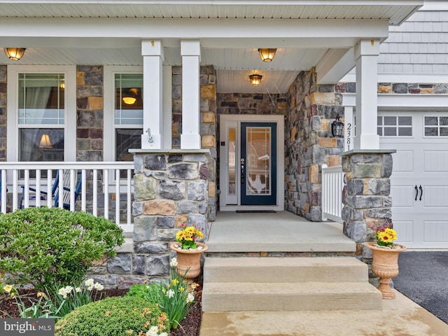 23811 Pembroke Ln, Millville, DE 19967 - view of exterior entry with covered porch, a garage, and stone siding
