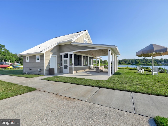 23811 Pembroke Ln, Millville, DE 19967 - view of side of property with a water view, a yard, a patio area, metal roof, and central air condition unit