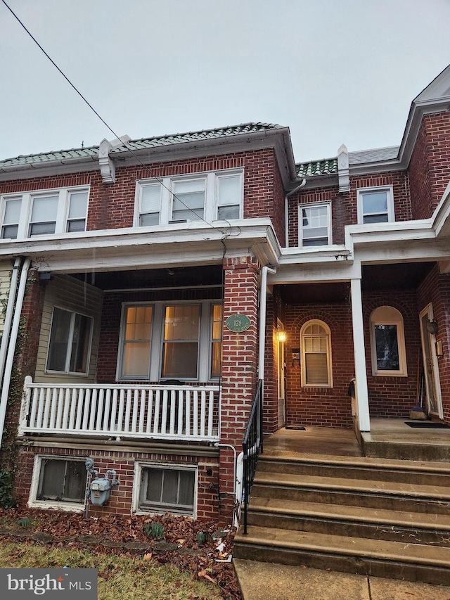 townhome / multi-family property with a porch and brick siding