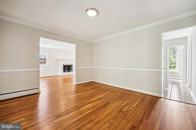 unfurnished living room featuring crown molding, a glass covered fireplace, baseboards, a baseboard radiator, and light wood finished floors