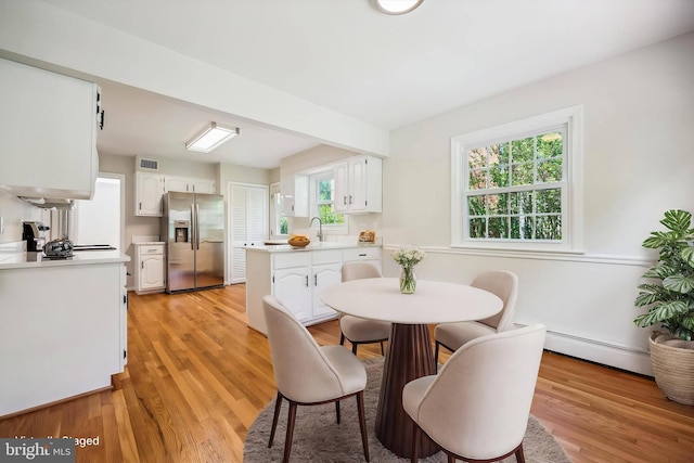 dining room featuring visible vents, light wood-type flooring, and a baseboard radiator