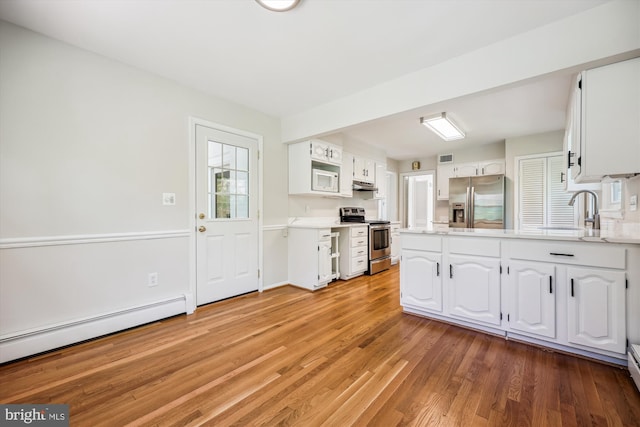 kitchen with light countertops, stainless steel appliances, white cabinetry, and a baseboard radiator