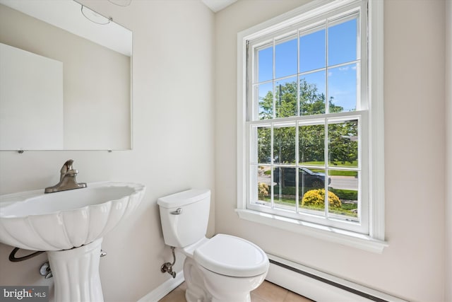 bathroom with baseboards, plenty of natural light, a baseboard heating unit, and toilet