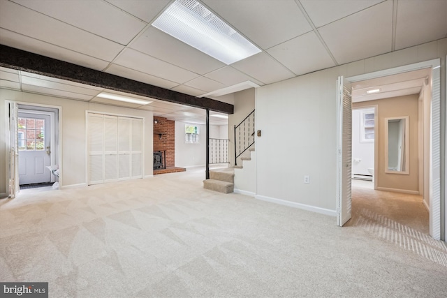 basement featuring carpet floors, a brick fireplace, baseboards, a baseboard radiator, and stairway