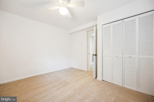 unfurnished bedroom with a closet, a ceiling fan, baseboards, and light carpet