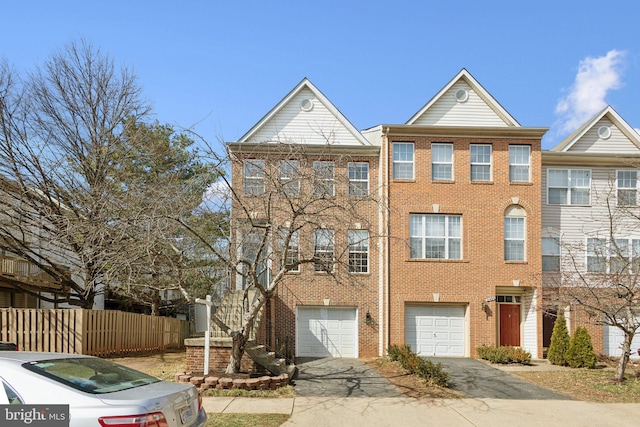 view of front facade featuring an attached garage, fence, brick siding, and driveway