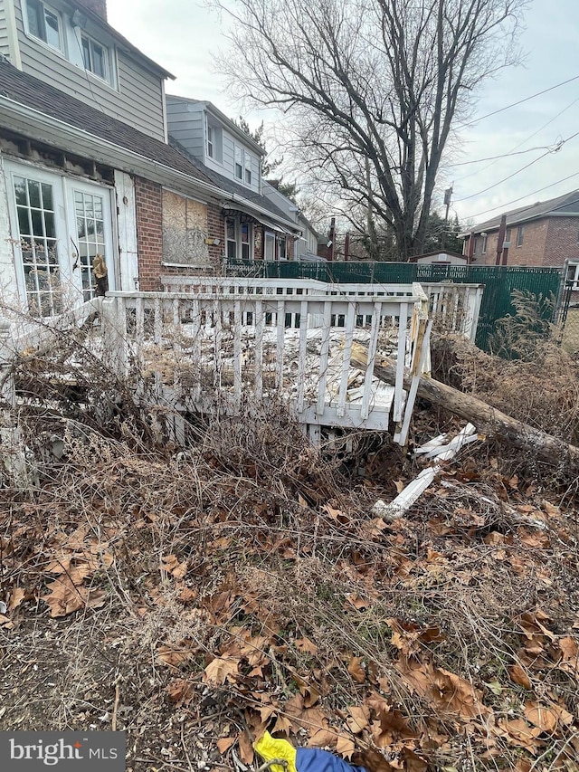 exterior details featuring brick siding, a shingled roof, and fence