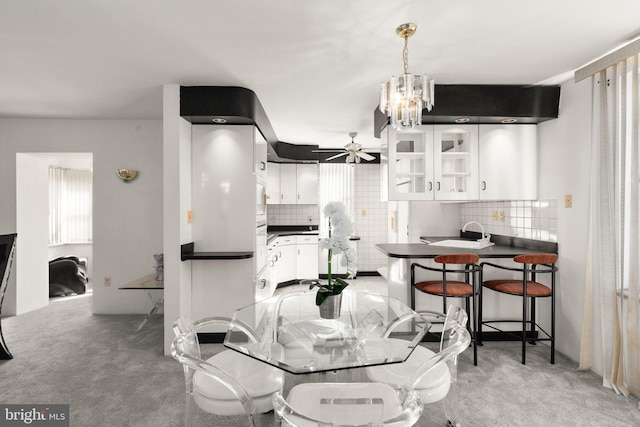 dining room with light carpet and ceiling fan with notable chandelier