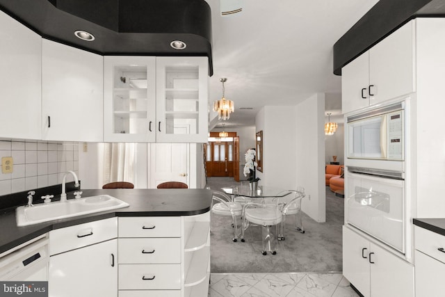 kitchen featuring a notable chandelier, marble finish floor, a sink, dark countertops, and white appliances