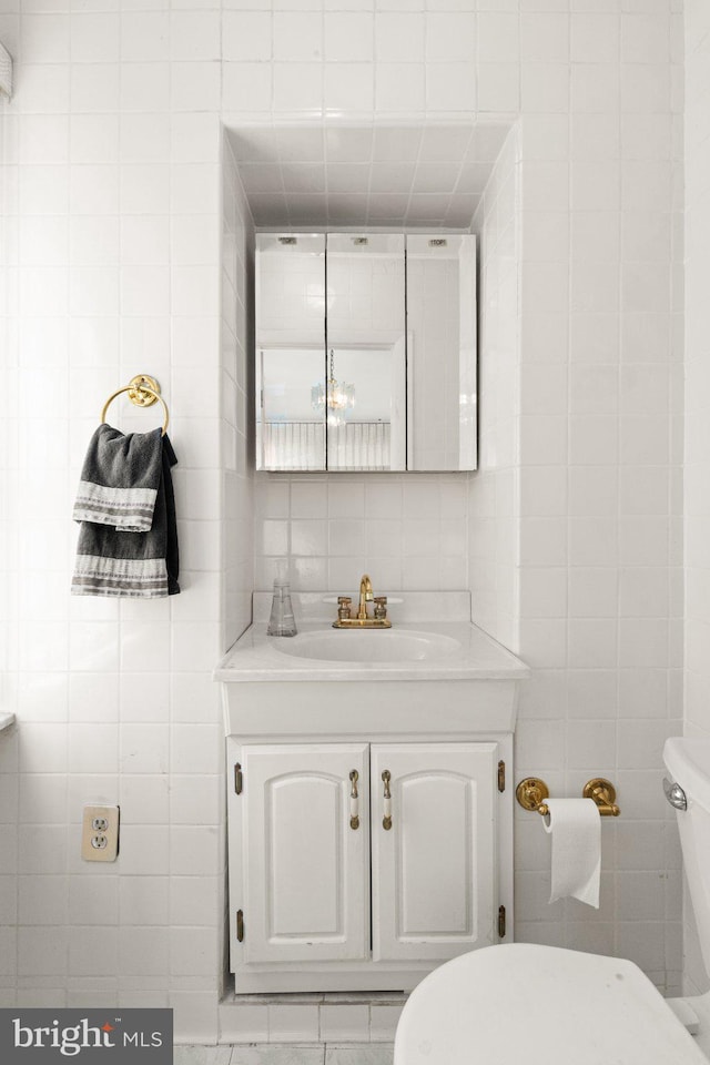 bathroom with vanity, tile walls, and toilet