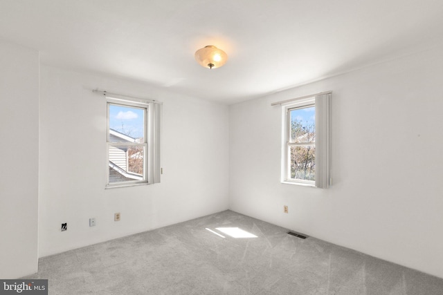 unfurnished room with visible vents, a healthy amount of sunlight, and carpet flooring