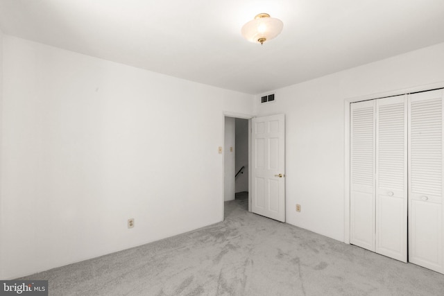 unfurnished bedroom featuring visible vents, a closet, and light carpet