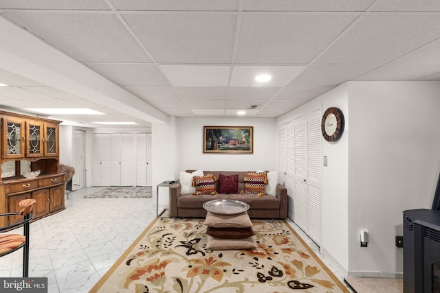 living room with a drop ceiling, baseboards, and marble finish floor