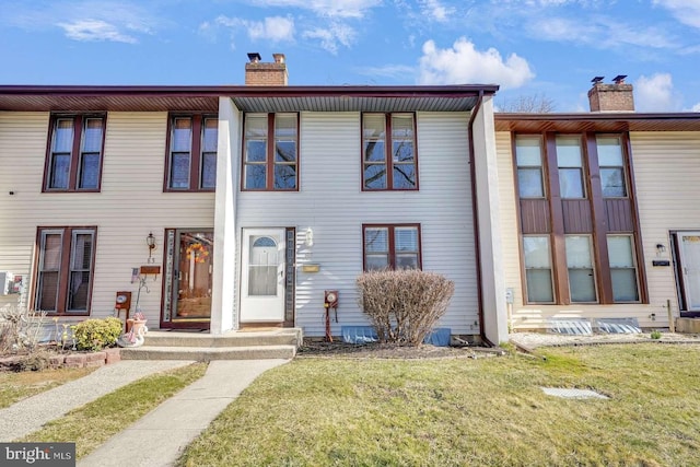 townhome / multi-family property with a chimney and a front lawn