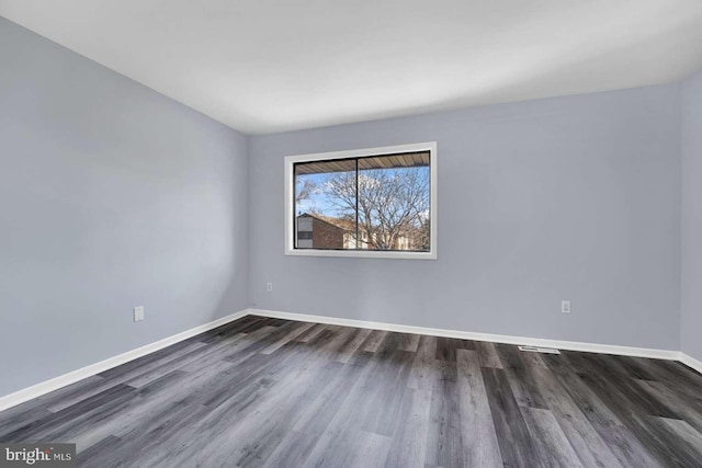 empty room with dark wood-type flooring and baseboards