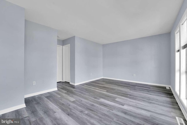 spare room with wood finished floors, visible vents, and baseboards