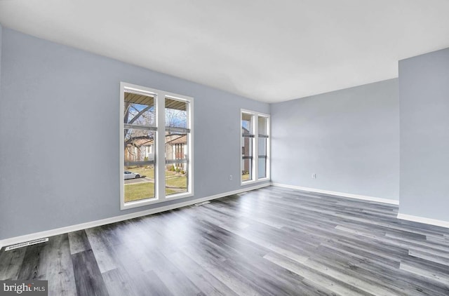 empty room featuring visible vents, baseboards, and wood finished floors